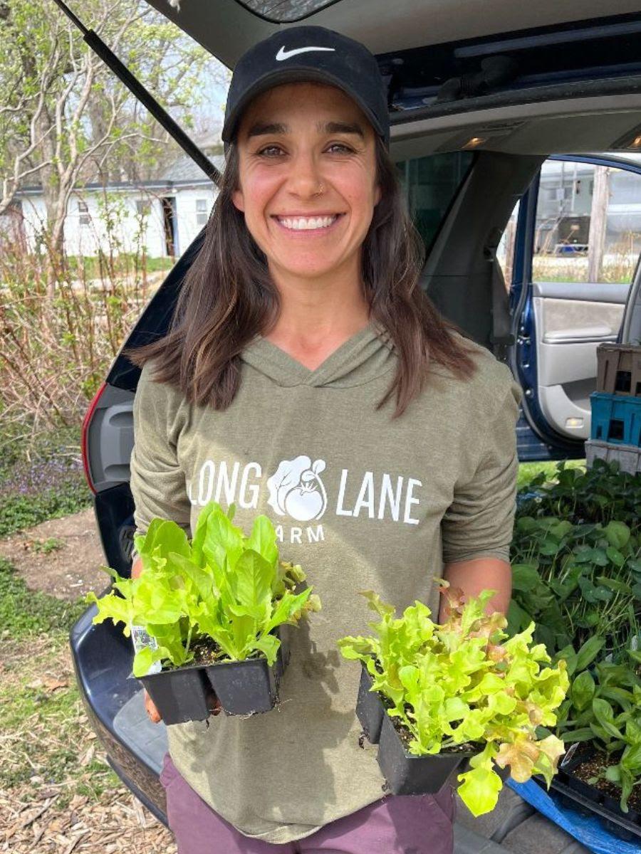 Camille Abdel Nabi wearing a Long Lane Farm sweatshirt and holding lettuce seedlings