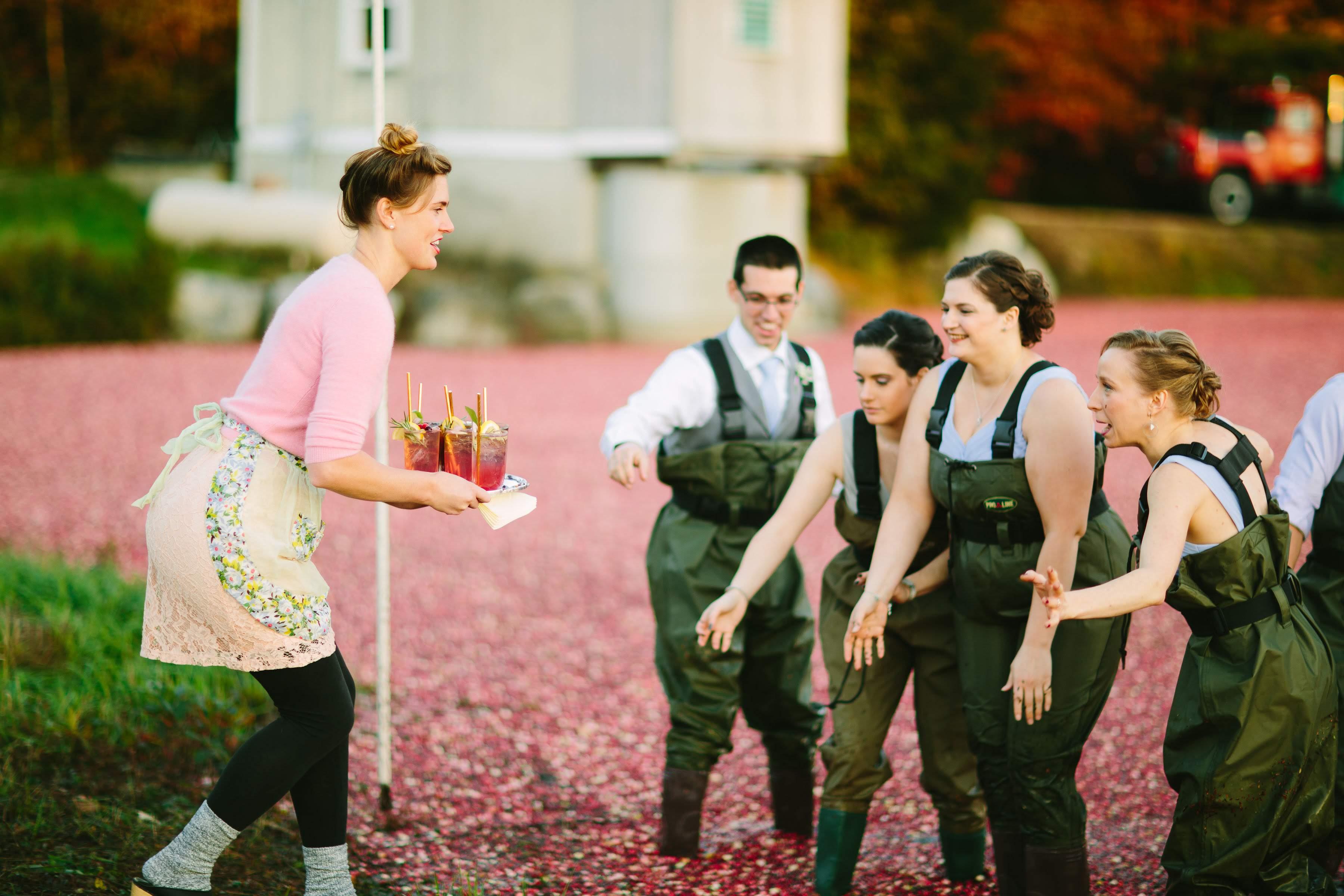 A group of people are being served cocktails while standing in a cranberry bog