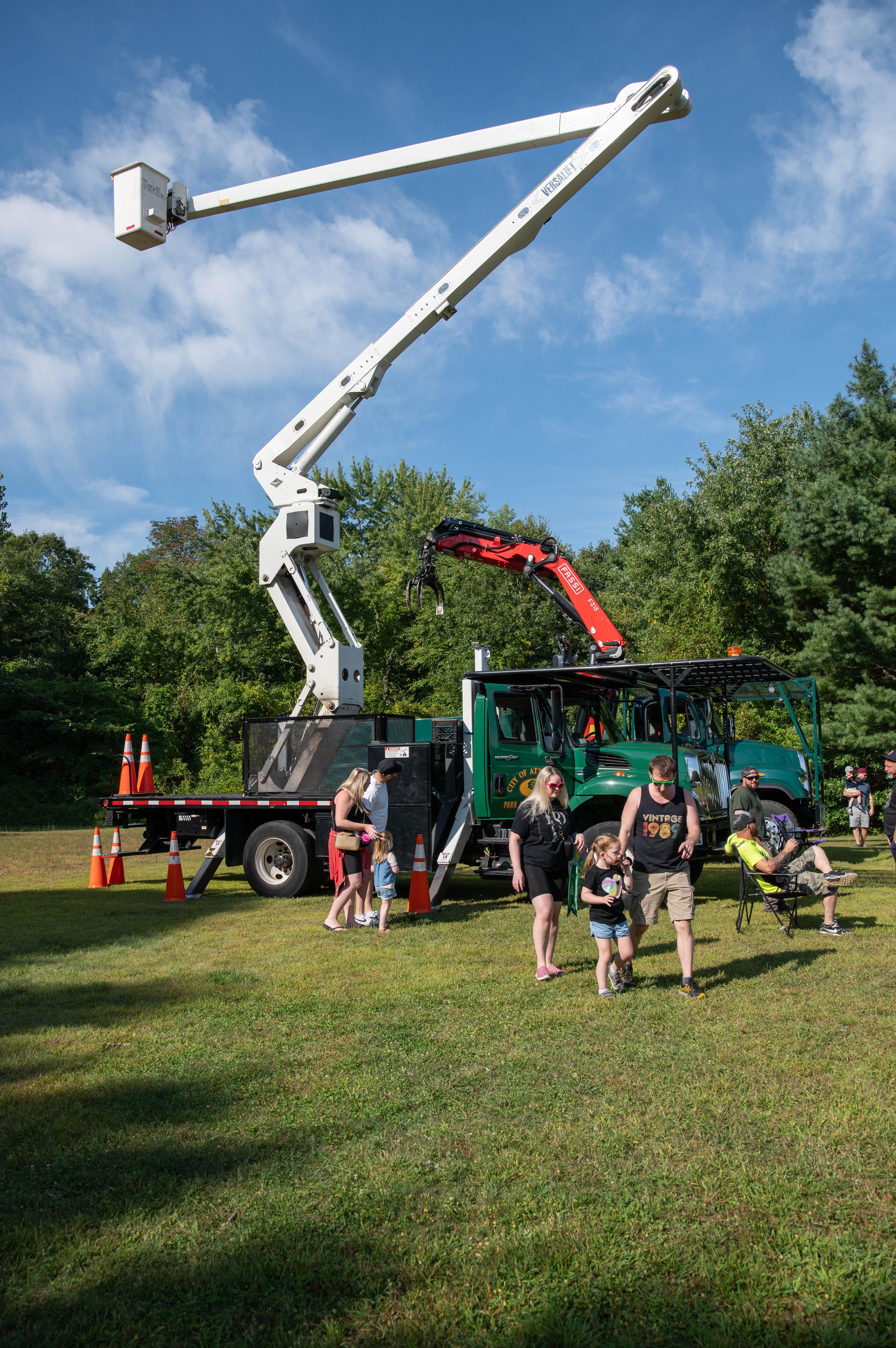 A truck with an extended boom and a family standing in front of it