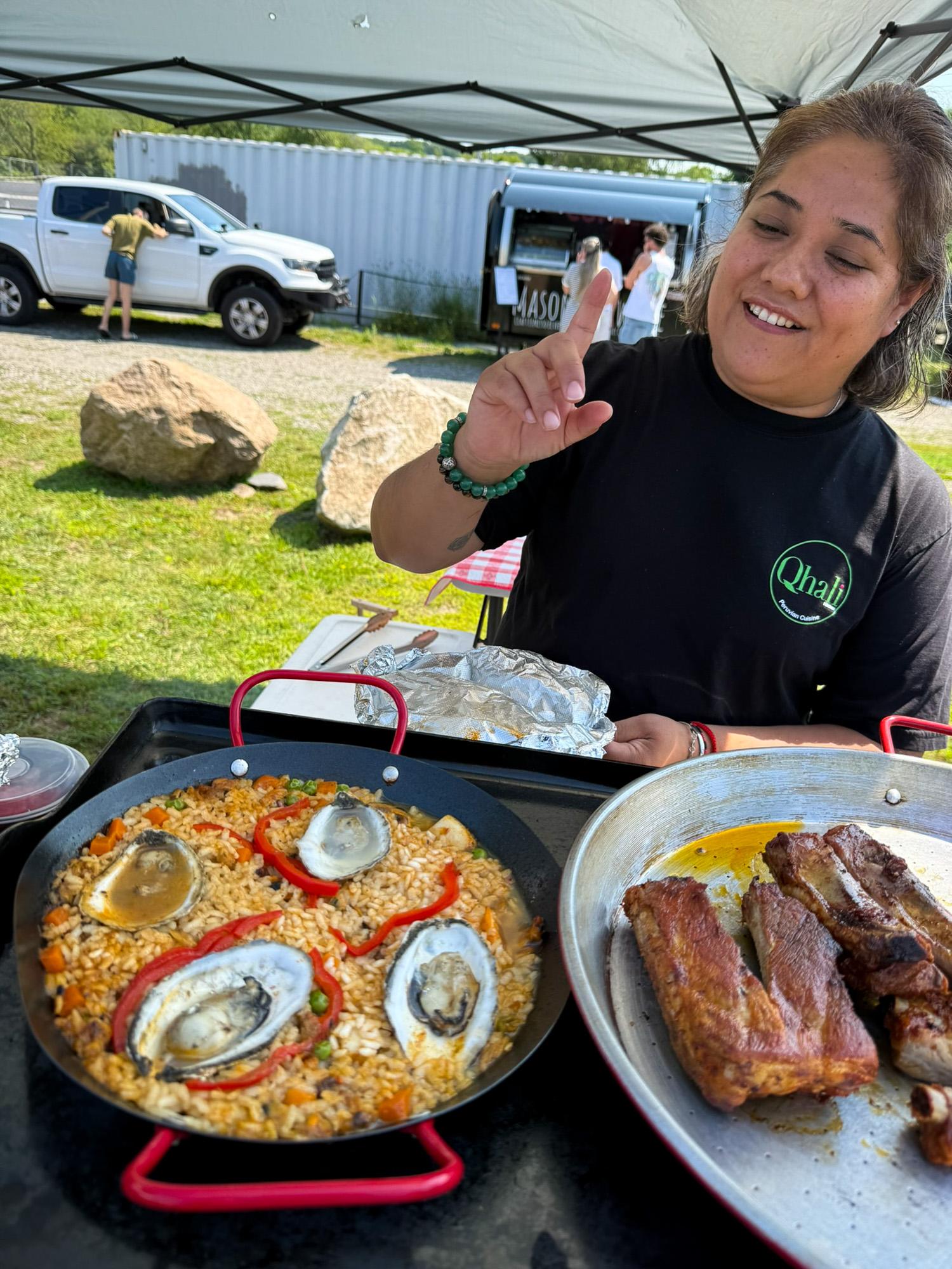 Vendor selling paella with oysters and grilled meats